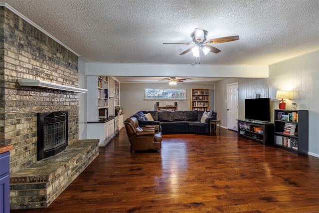 living room with a textured ceiling, ceiling fan, a fireplace, and dark hardwood / wood-style flooring