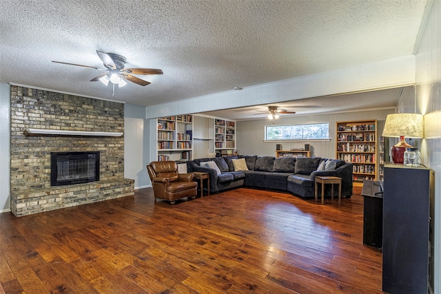 living room with ceiling fan, a fireplace, a textured ceiling, and dark hardwood / wood-style flooring