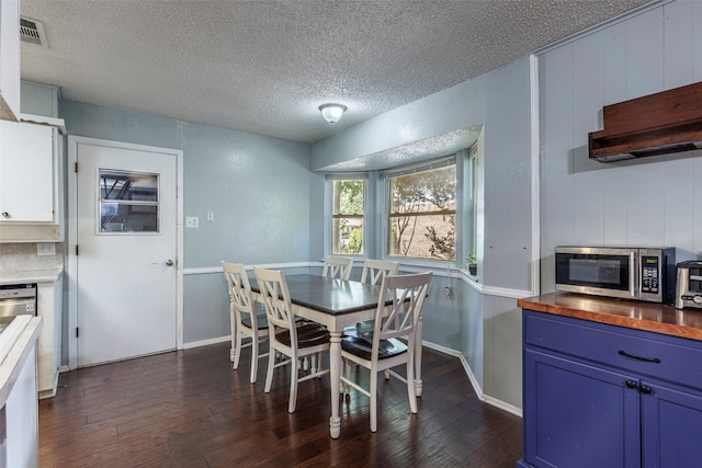 dining area with dark wood-type flooring and a textured ceiling