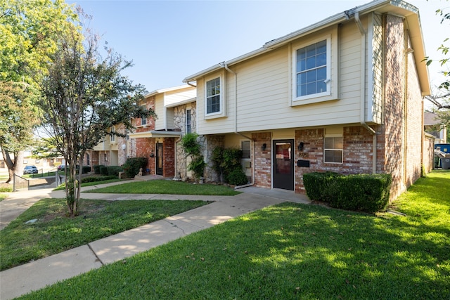 multi unit property featuring a front lawn and brick siding