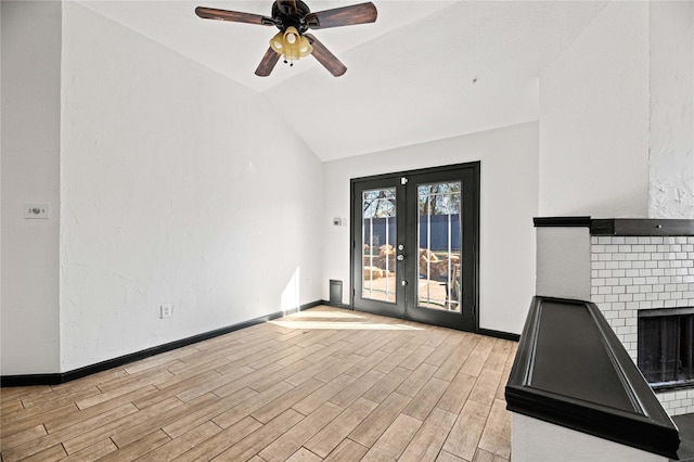 interior space featuring french doors, vaulted ceiling, ceiling fan, light hardwood / wood-style flooring, and a fireplace