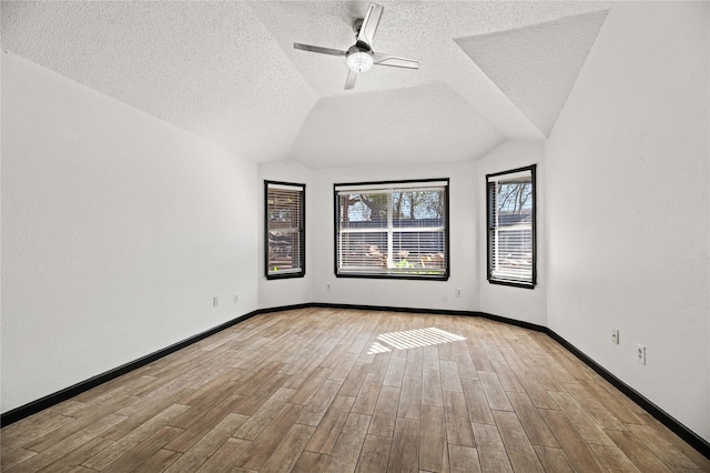 empty room with a textured ceiling, vaulted ceiling, and ceiling fan