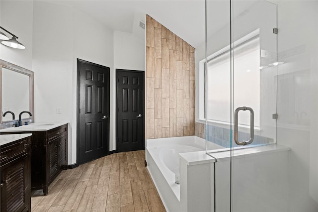 bathroom featuring plus walk in shower, vanity, and vaulted ceiling