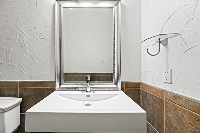 bathroom with tile walls, sink, and toilet