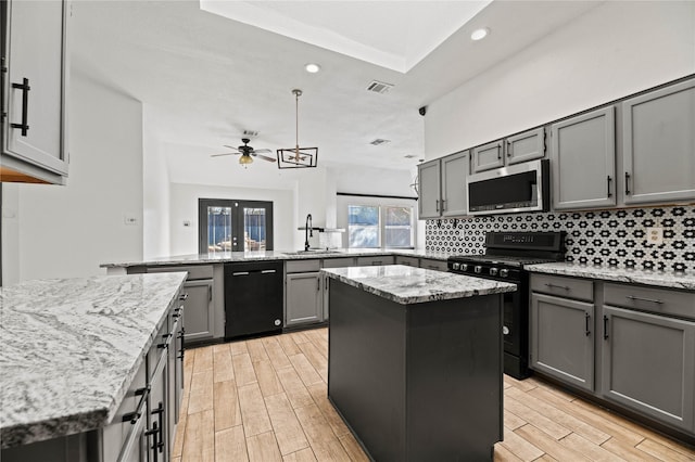 kitchen with ceiling fan, sink, kitchen peninsula, a kitchen island, and black appliances