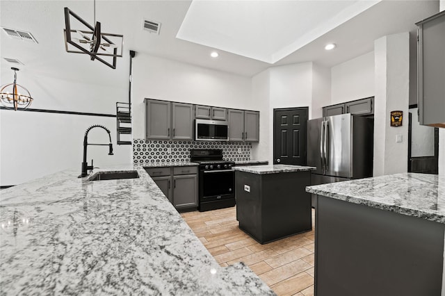 kitchen featuring light stone countertops, appliances with stainless steel finishes, a kitchen island, and sink