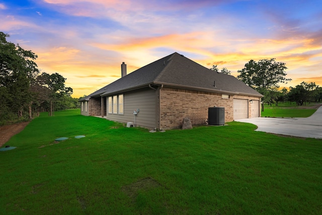 2201 Crystal Palace Blvd, Alvarado, TX 76009 - property exterior at dusk featuring a chimney, central AC unit, a yard, driveway, and brick siding