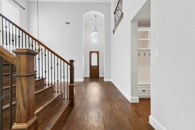 entryway featuring dark wood-type flooring and a towering ceiling