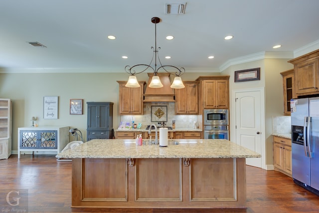 kitchen featuring dark wood-type flooring, stainless steel appliances, a center island with sink, and hanging light fixtures