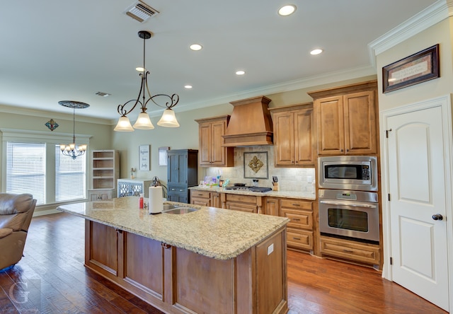 kitchen featuring dark wood-type flooring, appliances with stainless steel finishes, custom exhaust hood, and an island with sink