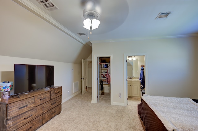 bedroom with connected bathroom, light carpet, a walk in closet, vaulted ceiling, and ceiling fan