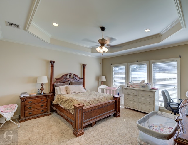 bedroom with ceiling fan, light carpet, a tray ceiling, and crown molding