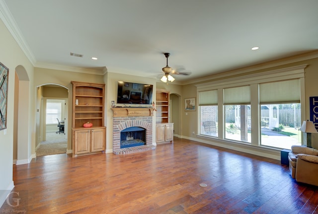 unfurnished living room with hardwood / wood-style flooring, ornamental molding, a wealth of natural light, and a fireplace