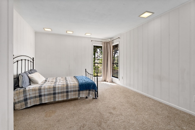 carpeted bedroom featuring ornamental molding and wooden walls