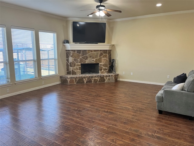 living room with dark wood-type flooring, a stone fireplace, crown molding, and ceiling fan