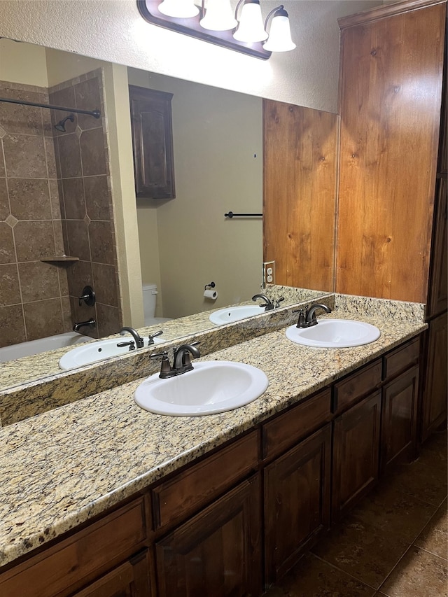 bathroom with vanity, a tile shower, toilet, and tile patterned flooring