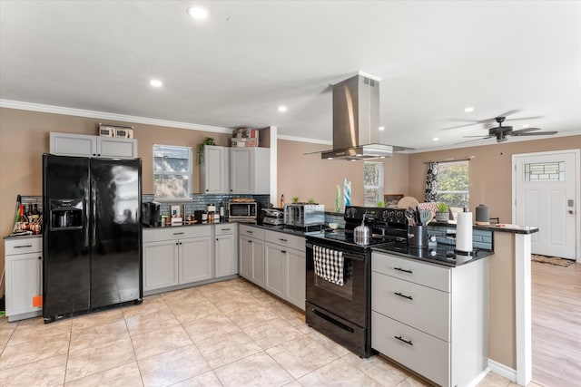 kitchen featuring kitchen peninsula, ceiling fan, island range hood, ornamental molding, and black appliances