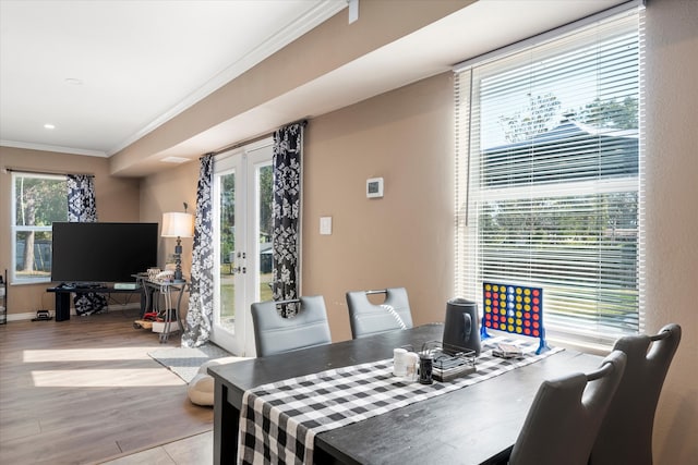 dining room featuring french doors, crown molding, and light wood-type flooring