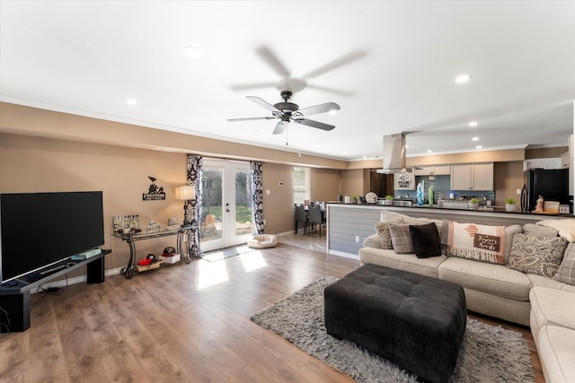 living room with french doors, ceiling fan, ornamental molding, and light wood-type flooring