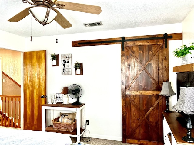 interior space featuring ceiling fan, a textured ceiling, and a barn door