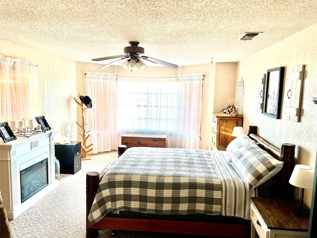 carpeted bedroom featuring ceiling fan and a textured ceiling