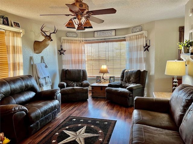 living room with a textured ceiling, dark wood-type flooring, and ceiling fan