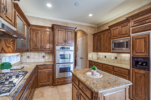 kitchen with light stone counters, appliances with stainless steel finishes, light tile patterned floors, and ornamental molding