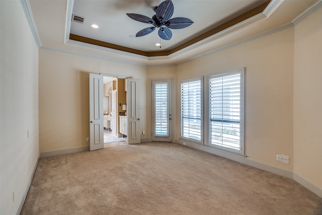 unfurnished room with light carpet, crown molding, a tray ceiling, and ceiling fan