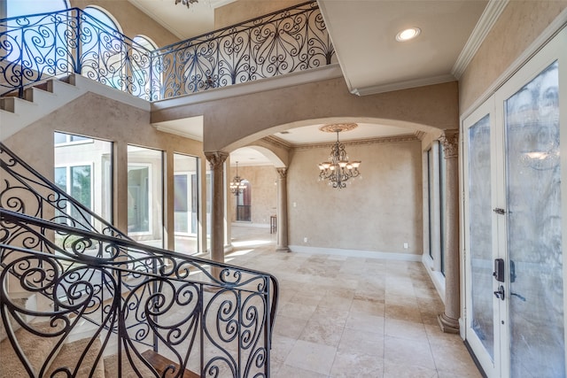 foyer featuring french doors, crown molding, decorative columns, and a towering ceiling