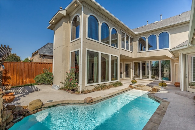 back of property with a patio and a fenced in pool