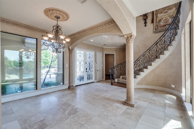 foyer entrance with french doors, a notable chandelier, crown molding, and decorative columns