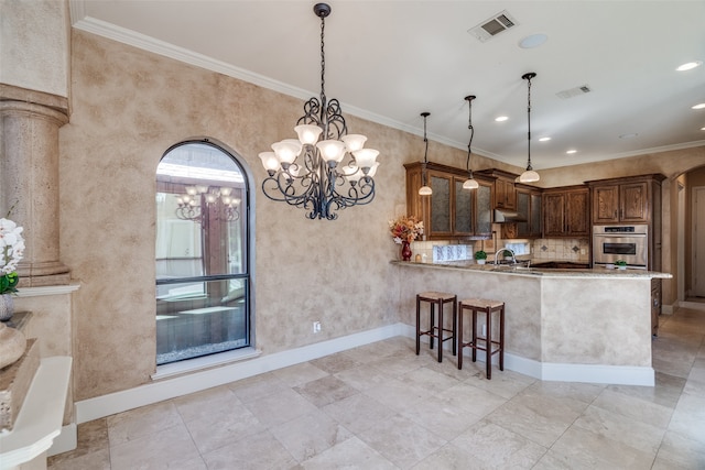 kitchen with kitchen peninsula, hanging light fixtures, ornate columns, and crown molding