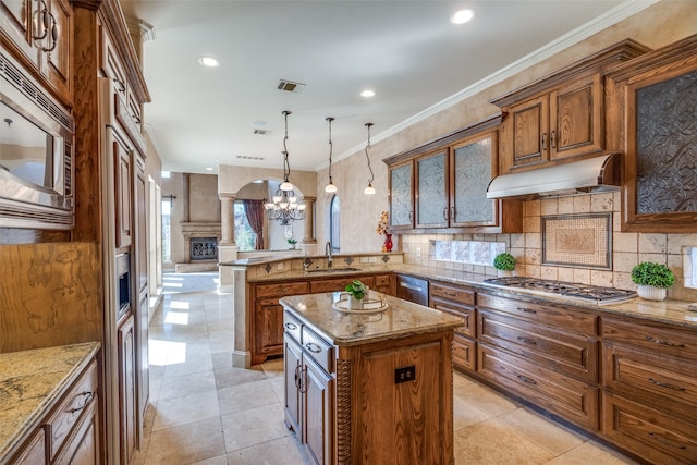 kitchen featuring ornate columns, kitchen peninsula, stainless steel appliances, a center island, and pendant lighting