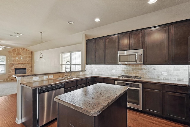 kitchen featuring appliances with stainless steel finishes, a center island, dark brown cabinetry, and lofted ceiling