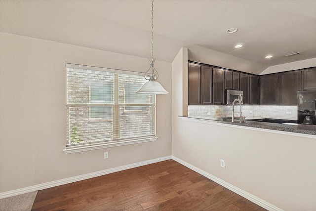 kitchen featuring lofted ceiling, backsplash, fridge, decorative light fixtures, and dark brown cabinetry