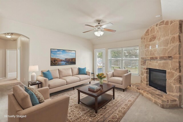 living room featuring ceiling fan, a fireplace, and lofted ceiling