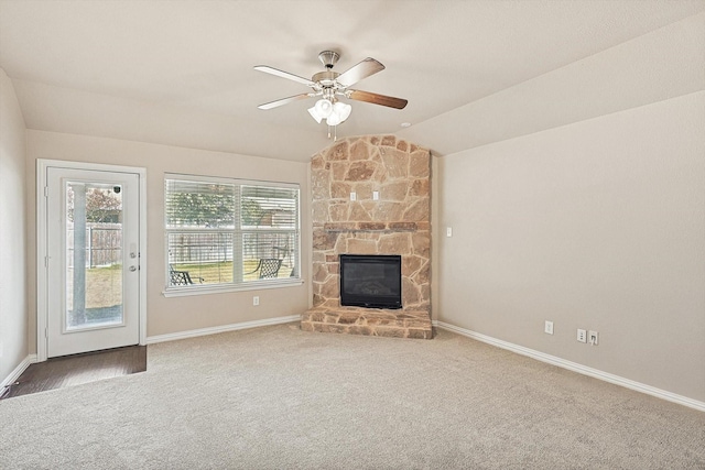 unfurnished living room with carpet floors, vaulted ceiling, ceiling fan, and a stone fireplace