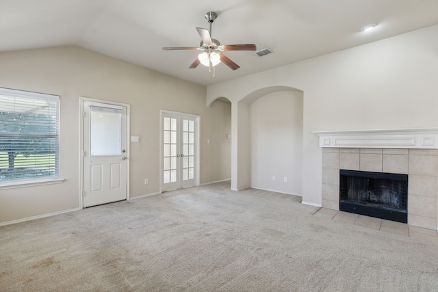 unfurnished living room with lofted ceiling, light carpet, a tiled fireplace, and ceiling fan