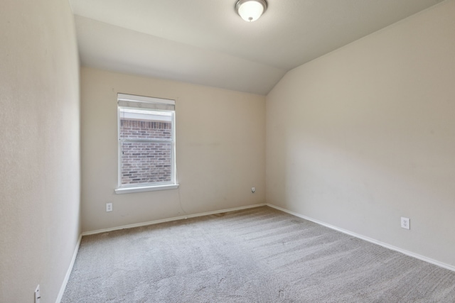 carpeted spare room featuring vaulted ceiling