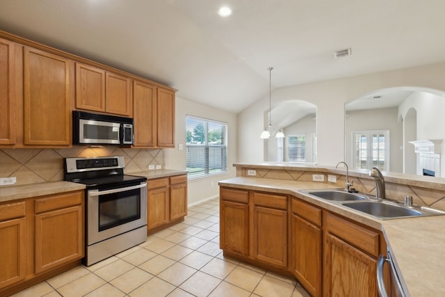 kitchen with appliances with stainless steel finishes, sink, vaulted ceiling, decorative light fixtures, and decorative backsplash