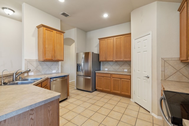 kitchen with light tile patterned floors, stainless steel appliances, tasteful backsplash, and sink