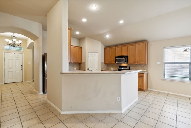 kitchen featuring appliances with stainless steel finishes, light tile patterned floors, backsplash, and vaulted ceiling