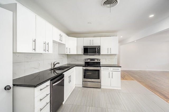 kitchen featuring sink, appliances with stainless steel finishes, light hardwood / wood-style floors, white cabinets, and decorative backsplash