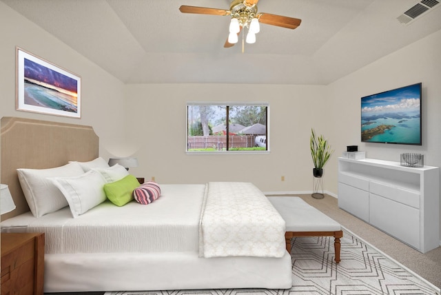 bedroom with light carpet, ceiling fan, and a tray ceiling