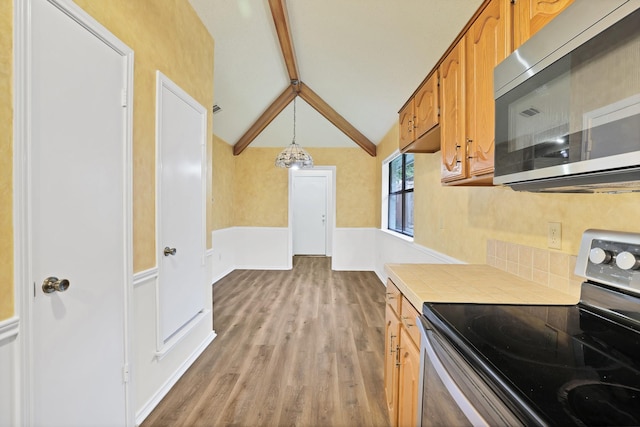 kitchen with tile countertops, lofted ceiling with beams, light wood-type flooring, pendant lighting, and stainless steel appliances