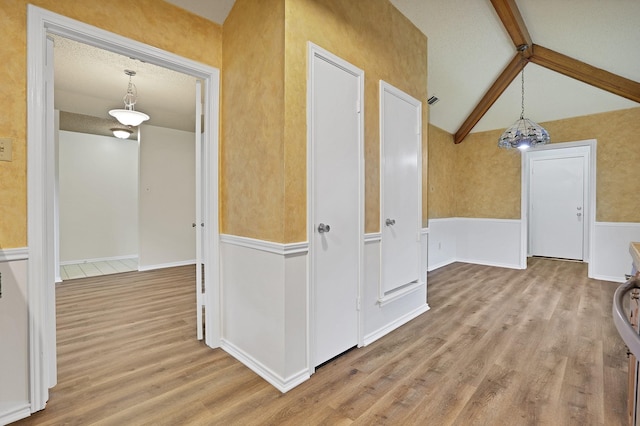 interior space featuring vaulted ceiling with beams and light hardwood / wood-style flooring