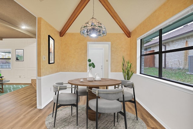 dining area featuring hardwood / wood-style floors and vaulted ceiling with beams