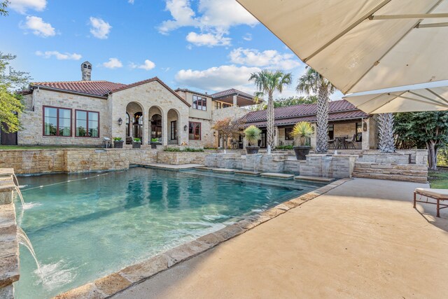 pool at dusk featuring a patio area and pool water feature