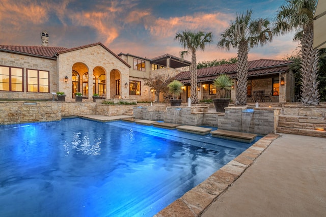 pool at dusk featuring a patio area