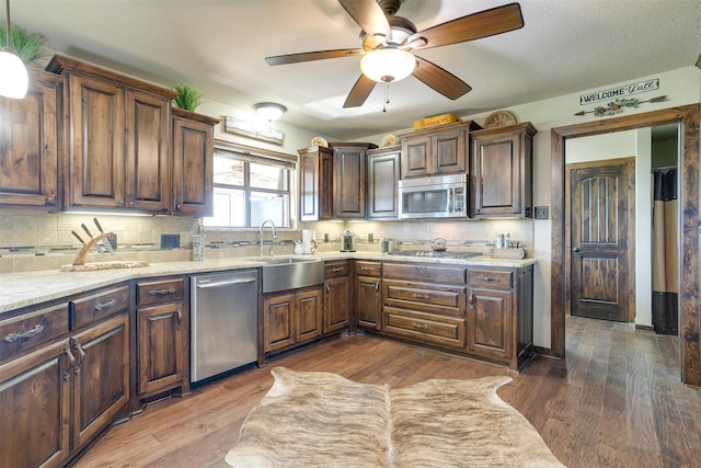 kitchen featuring backsplash, appliances with stainless steel finishes, dark brown cabinets, dark hardwood / wood-style floors, and sink